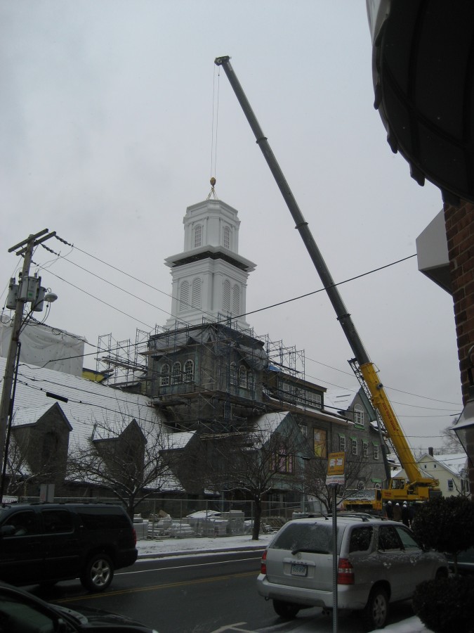 Louvered section of church steeple being lowered in place